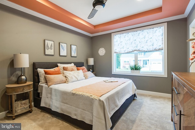 carpeted bedroom featuring ceiling fan, crown molding, and a tray ceiling