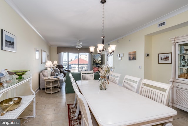 tiled dining room with ceiling fan with notable chandelier and ornamental molding