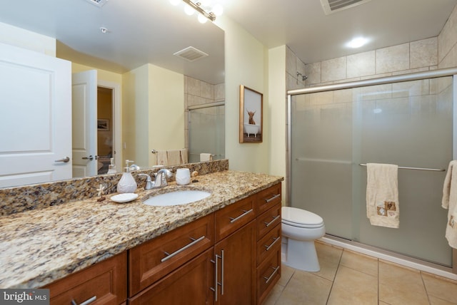 bathroom with tile patterned floors, toilet, vanity, and walk in shower