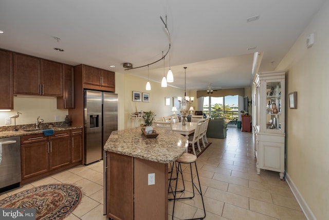 kitchen featuring stainless steel appliances, sink, light tile patterned floors, a kitchen island, and a breakfast bar area