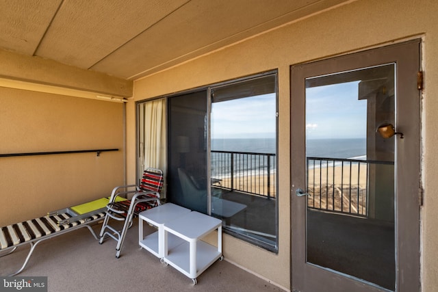 balcony featuring a water view and a beach view