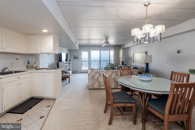 tiled dining space with ceiling fan with notable chandelier, baseboard heating, and sink