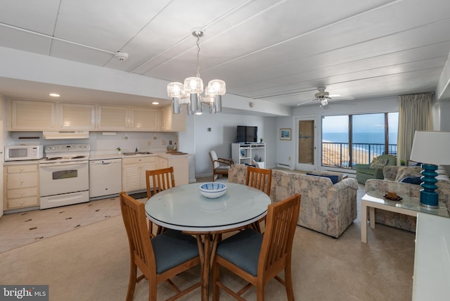 dining area with sink and ceiling fan with notable chandelier