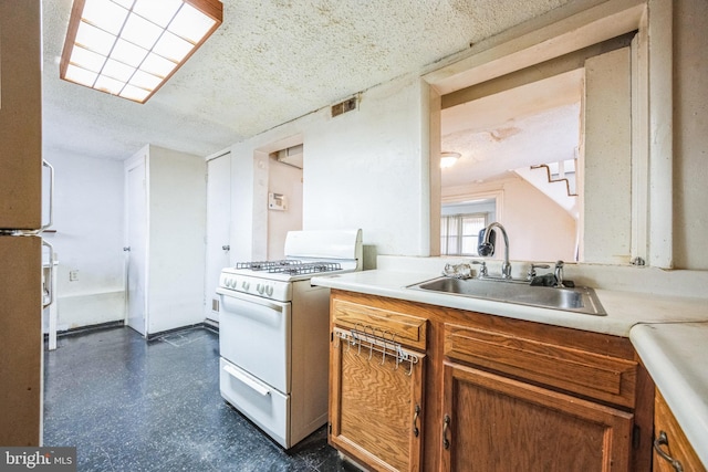 kitchen featuring white gas range, sink, and a textured ceiling