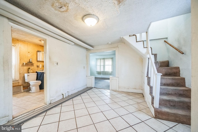 stairs featuring tile patterned floors and a textured ceiling