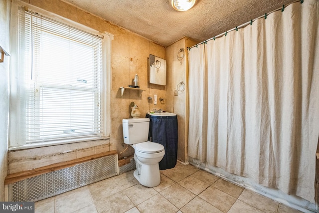 bathroom with toilet, radiator, tile patterned floors, and wood walls