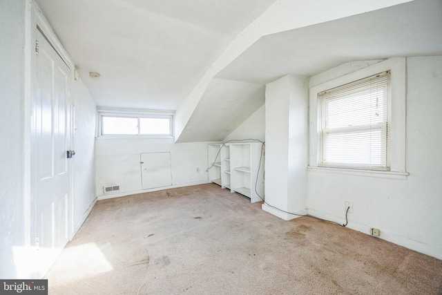 bonus room with lofted ceiling and light carpet