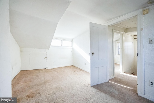 additional living space featuring vaulted ceiling and light colored carpet