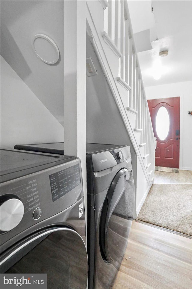 laundry area featuring washing machine and clothes dryer and light hardwood / wood-style floors