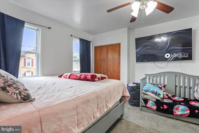 bedroom with ceiling fan, light carpet, and a closet