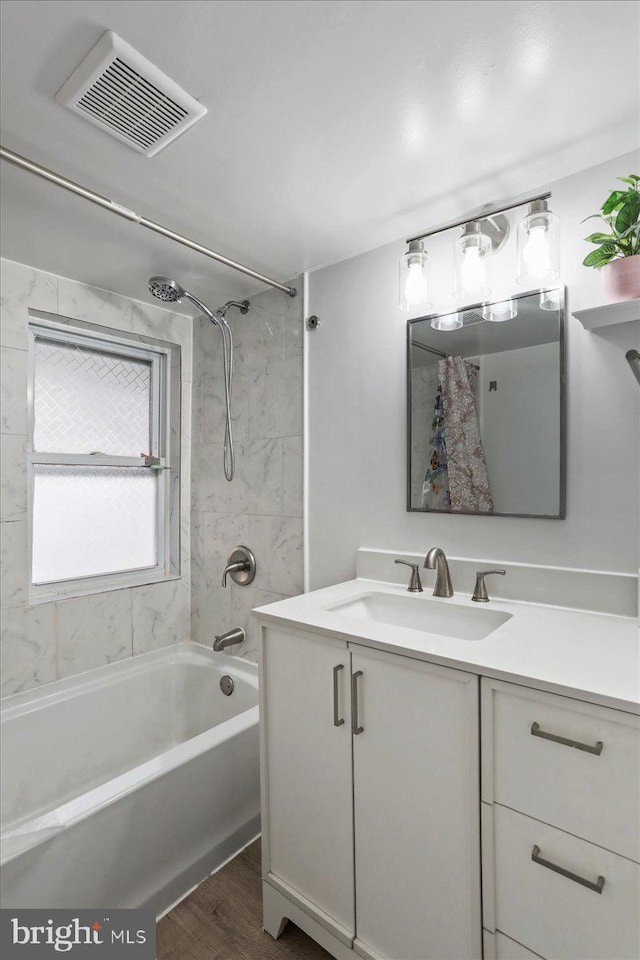 bathroom featuring hardwood / wood-style floors, vanity, and tiled shower / bath