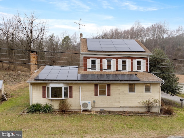 rear view of property featuring a yard, ac unit, and solar panels