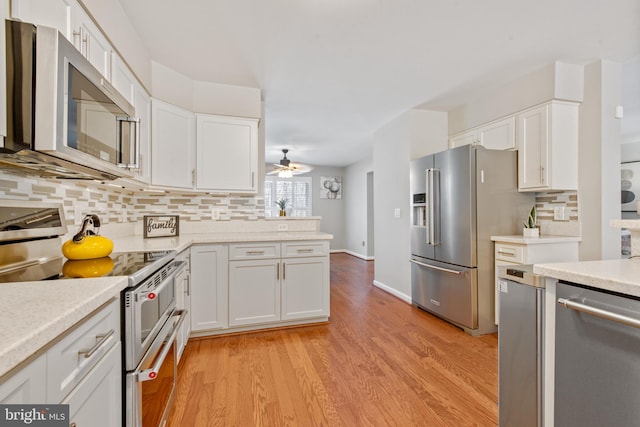 kitchen with decorative backsplash, appliances with stainless steel finishes, ceiling fan, white cabinets, and light hardwood / wood-style floors