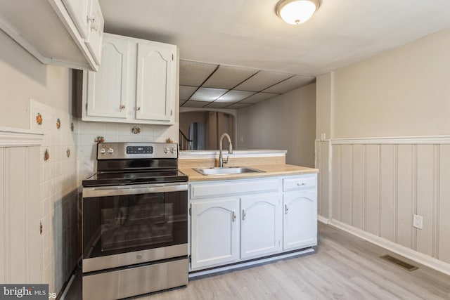 kitchen with white cabinets, sink, stainless steel range with electric cooktop, and light hardwood / wood-style flooring