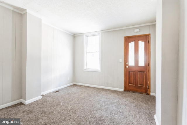 carpeted entryway with ornamental molding and a textured ceiling