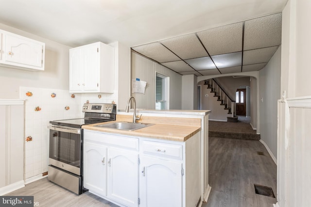 kitchen with sink, stainless steel range with electric cooktop, light hardwood / wood-style floors, a paneled ceiling, and white cabinets