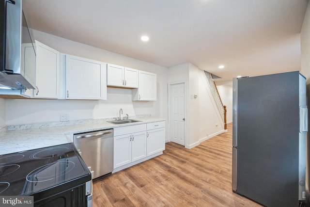 kitchen with sink, white cabinets, light hardwood / wood-style flooring, and appliances with stainless steel finishes