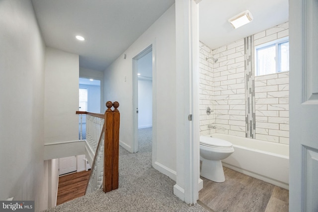 bathroom with tiled shower / bath combo, hardwood / wood-style flooring, and toilet