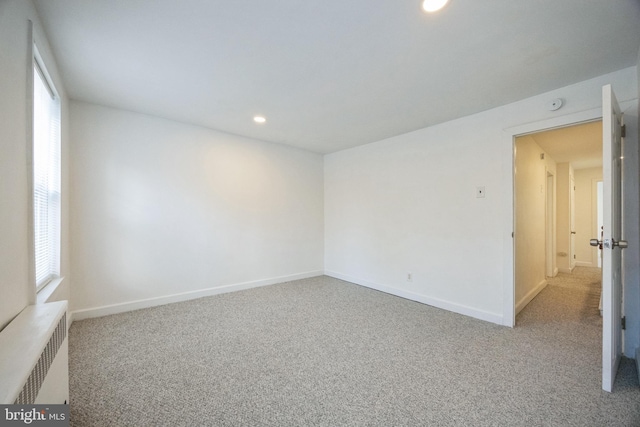 carpeted empty room featuring radiator heating unit