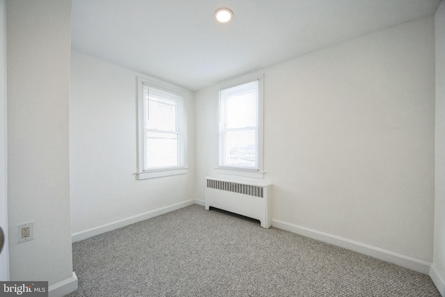 unfurnished room with carpet and radiator