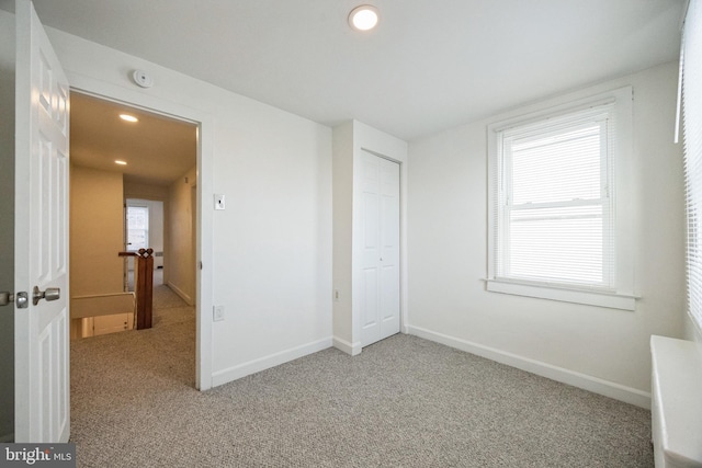 unfurnished bedroom featuring carpet, multiple windows, and a closet