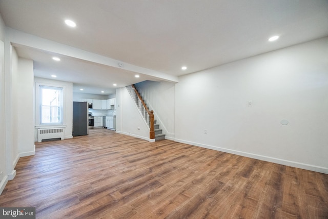 unfurnished living room with radiator and light wood-type flooring