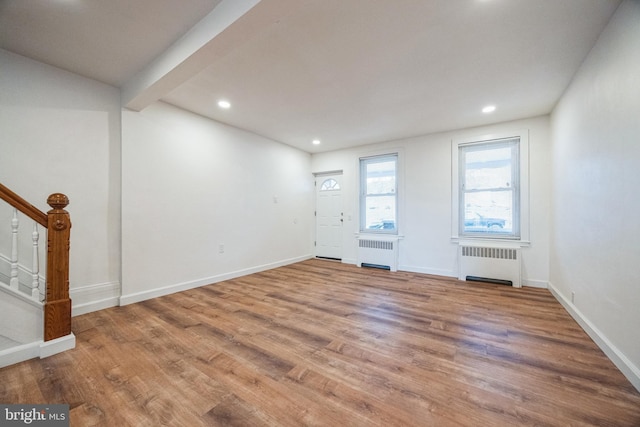 interior space featuring beamed ceiling, hardwood / wood-style flooring, and radiator