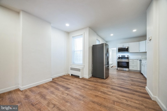 kitchen featuring white cabinets, dark hardwood / wood-style flooring, stainless steel appliances, and radiator