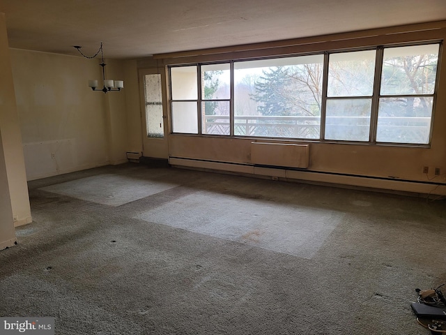 spare room with a baseboard radiator, carpet, and a notable chandelier