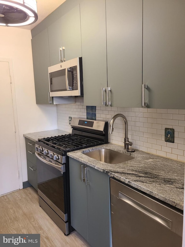 kitchen with stainless steel appliances, light hardwood / wood-style flooring, tasteful backsplash, and sink