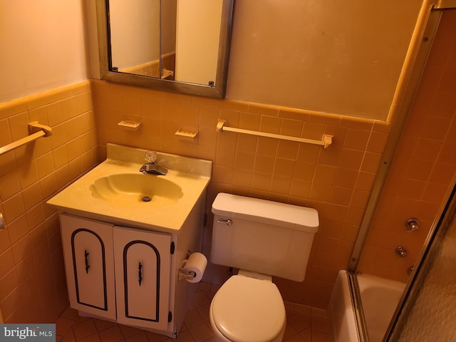 full bathroom featuring bath / shower combo with glass door, tile walls, toilet, and vanity