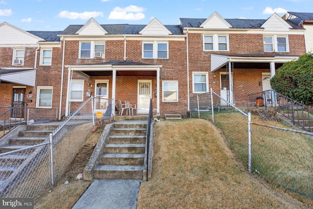 townhome / multi-family property featuring covered porch and a front yard