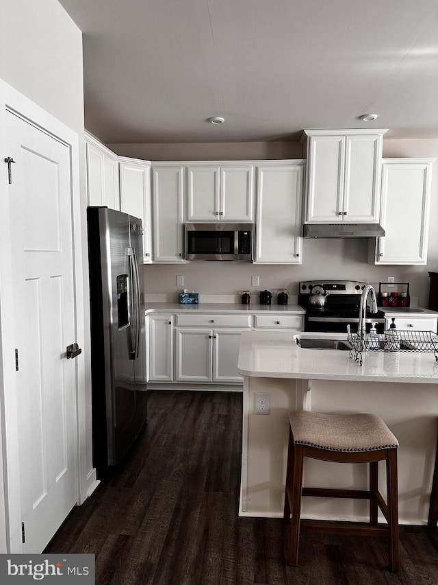 kitchen featuring sink, white cabinetry, stainless steel appliances, dark hardwood / wood-style floors, and light stone countertops