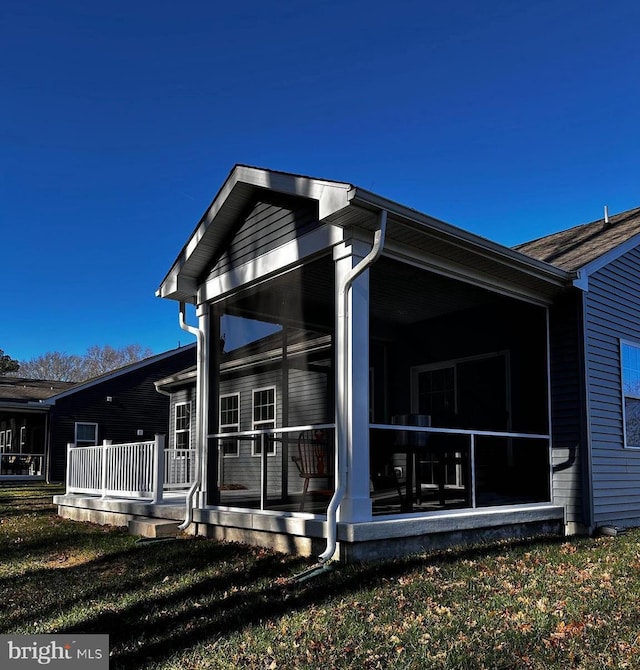 view of side of property with a sunroom and a lawn