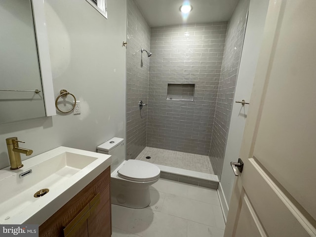 bathroom with a tile shower, vanity, and toilet