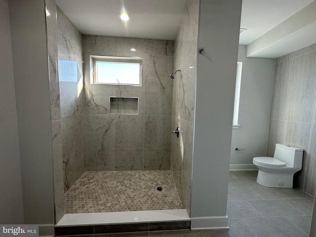 bathroom with tiled shower, tile patterned flooring, and toilet