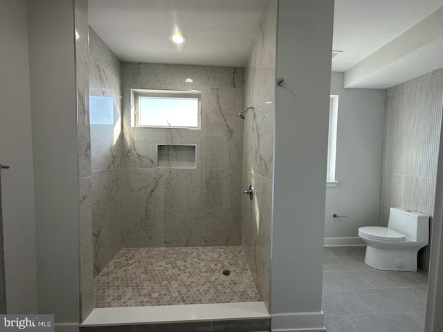 bathroom featuring a tile shower and toilet