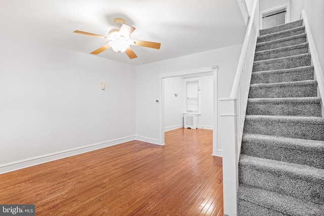 stairs with ceiling fan, radiator heating unit, and wood-type flooring