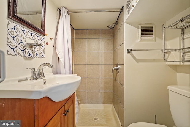 bathroom with tiled shower, vanity, and toilet