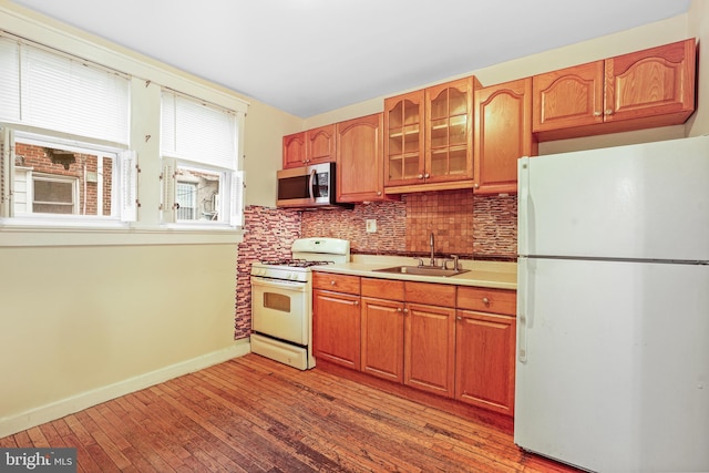 kitchen featuring white appliances, light hardwood / wood-style floors, tasteful backsplash, and sink