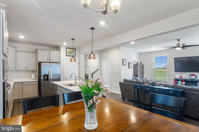 dining room with ceiling fan with notable chandelier, dark hardwood / wood-style floors, and sink