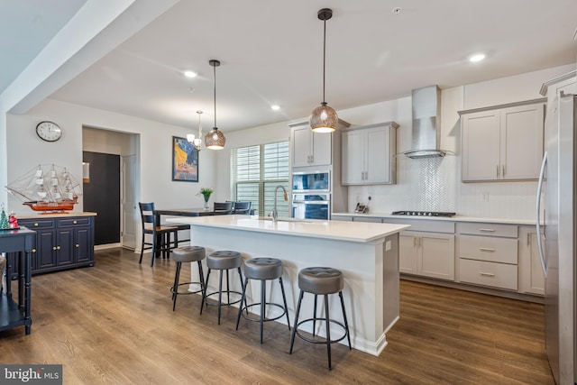 kitchen featuring wall chimney exhaust hood, stainless steel appliances, and wood-type flooring