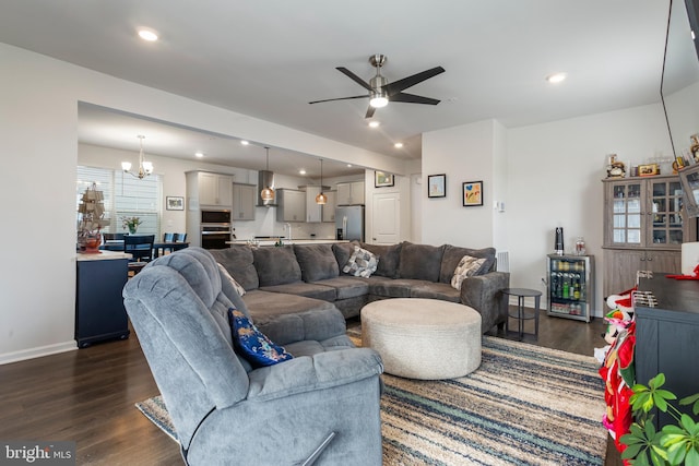 living room with dark wood-type flooring and ceiling fan with notable chandelier