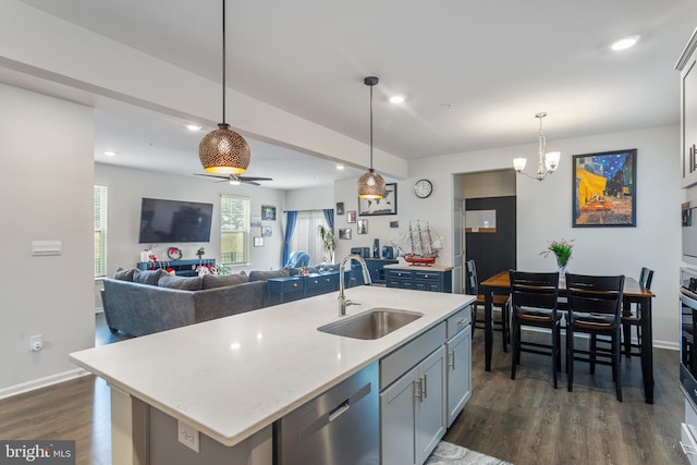 kitchen with a center island with sink, dishwasher, sink, and decorative light fixtures