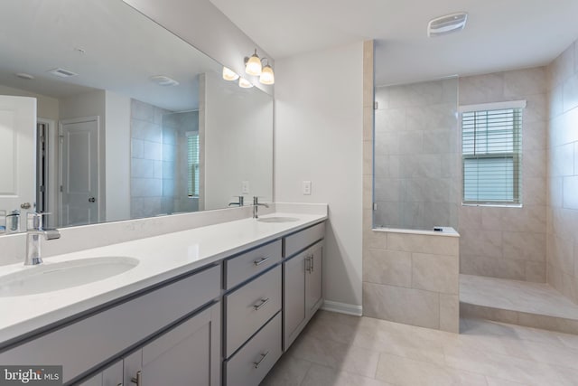 bathroom with tile patterned flooring, vanity, and tiled shower