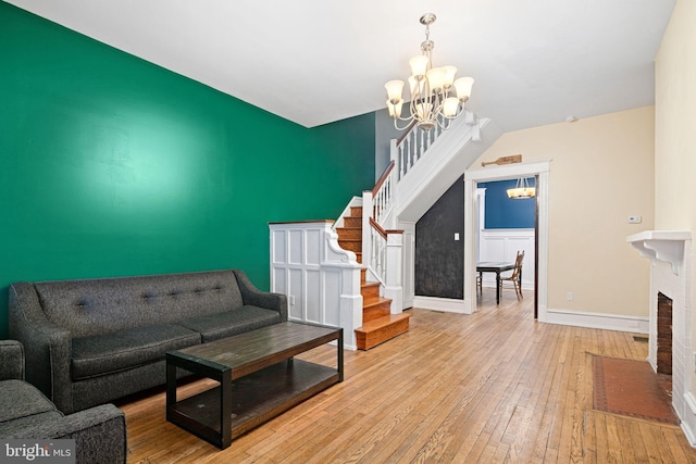 living room featuring a notable chandelier, light wood-type flooring, and a brick fireplace