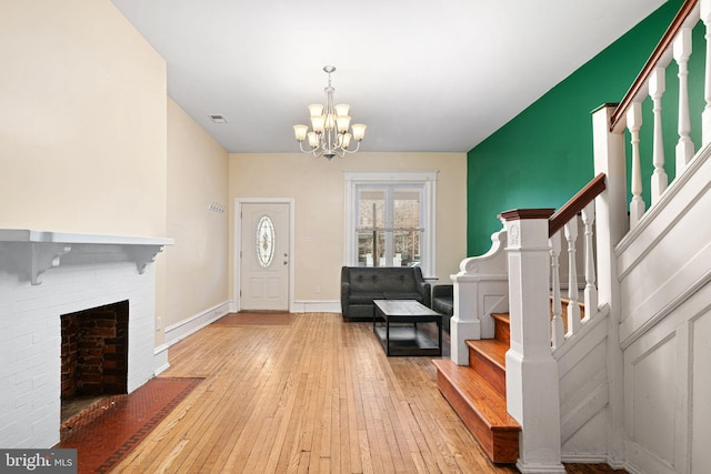 entryway featuring light hardwood / wood-style flooring, a notable chandelier, and a brick fireplace