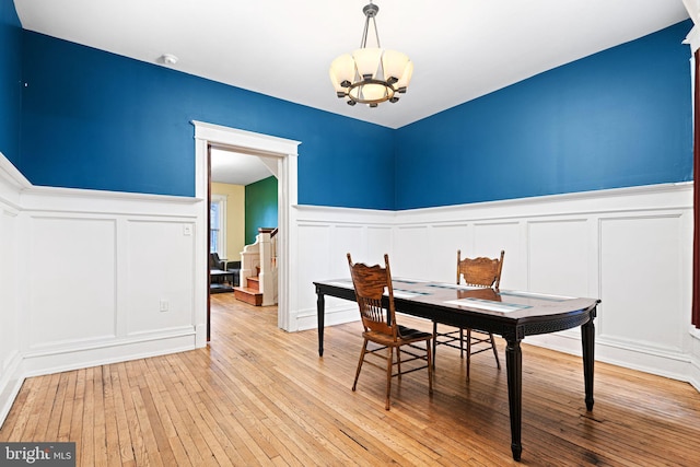 dining area with light wood-type flooring and a notable chandelier