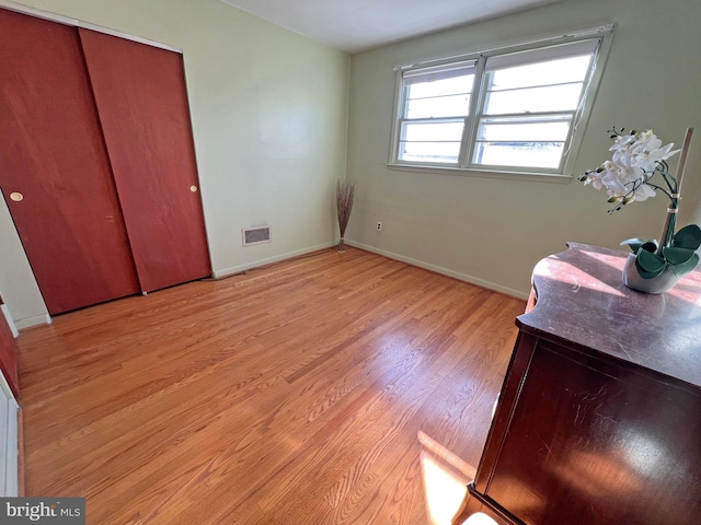 bedroom with light hardwood / wood-style floors and a closet