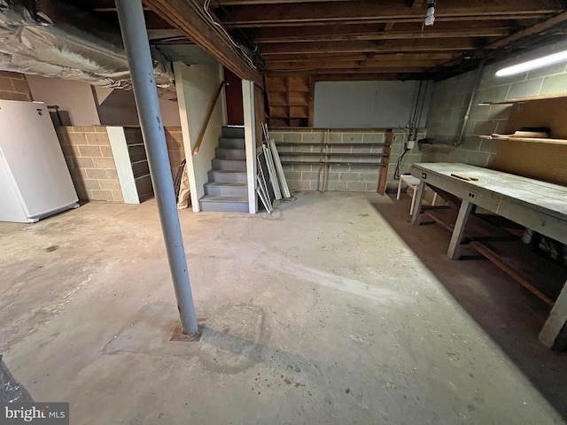 basement with a workshop area and white refrigerator